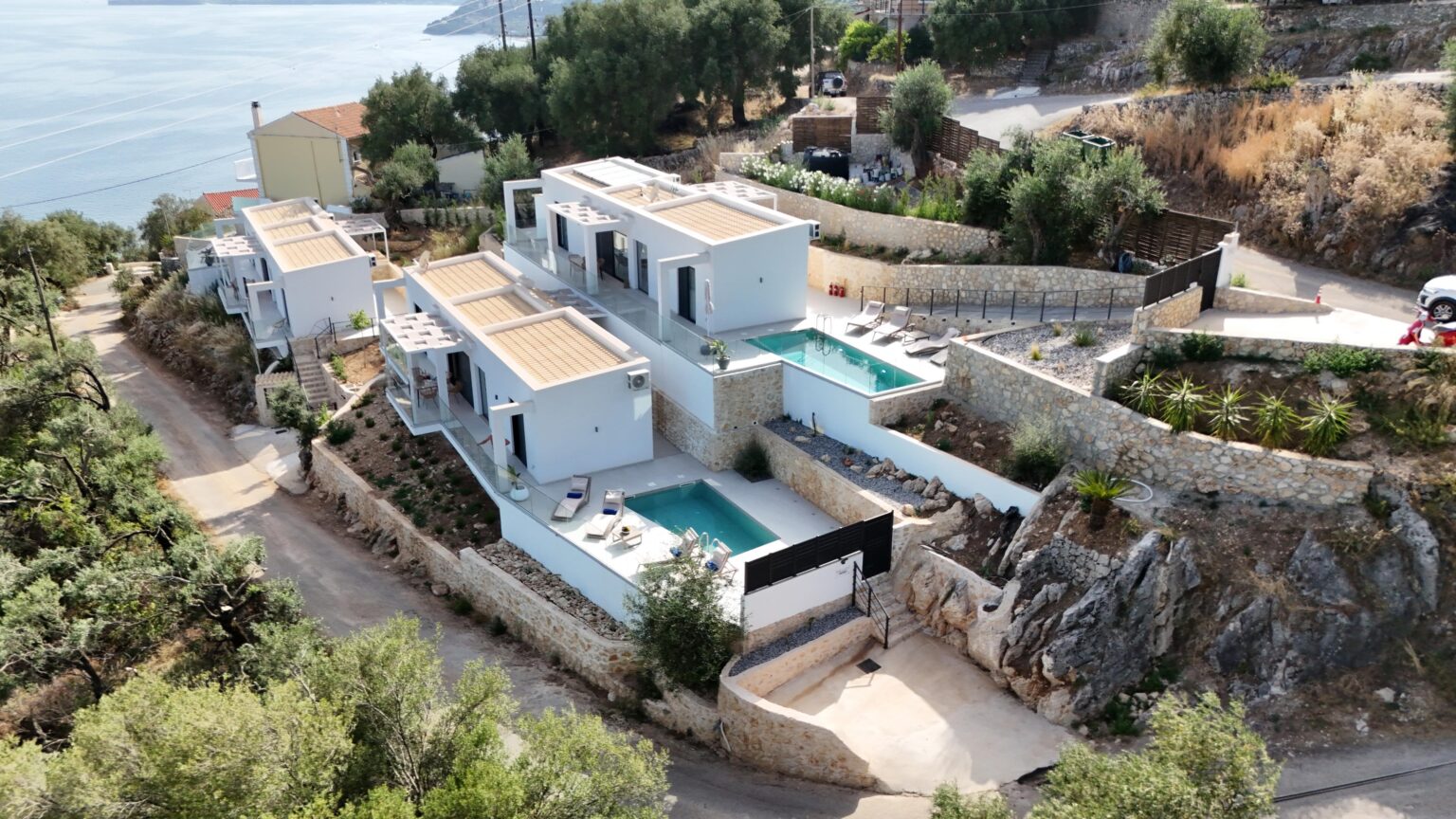 Drone view of the three Nissaki Villas with private pools on the Corfu hillside